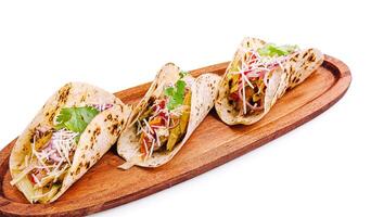 Delicious tacos served on a wooden platter with fresh ingredients photo