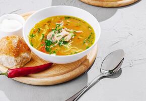 Delicious chicken noodle soup served with fresh bread and chili photo