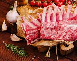 Fresh lamb chops with herbs and garlic on rustic wooden table photo