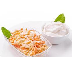 Creamy coleslaw with a side of yogurt served in a clear dish photo