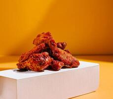 Delicious spicy chicken wings stacked on a clean white box photo