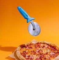 Pizza cutter hovering above a delicious pepperoni pizza photo