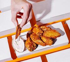 Crispy chicken wings served with dipping sauce on bright background photo