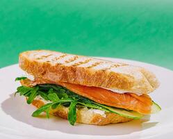 Delicious salmon sandwich with arugula and cucumber on toasted bread photo