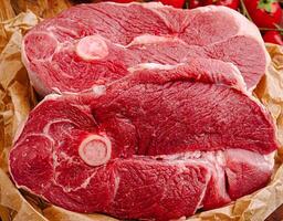 Fresh red meat cuts displayed on butcher paper with tomatoes photo