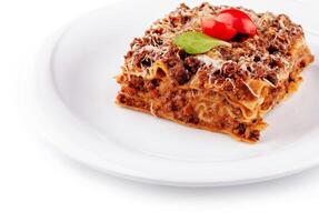 Portion of lasagna sitting on a white plate close up photo