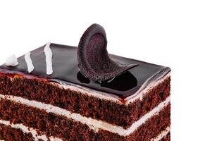 Chocolate cake slice decorated with chocolate curls and glaze on white background photo