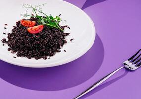 Delicious black rice dish garnished with fresh tomatoes and herbs photo