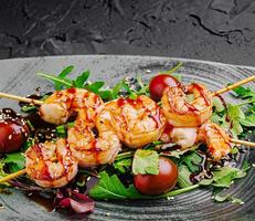 Grilled shrimp skewers served on fresh greens with sauce drizzle photo