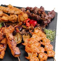 Delicious mixed grill platter featuring skewers of meat and seafood photo