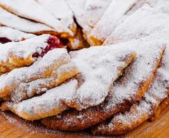 Freshly baked cherry pie with sugar powder on a wooden board photo