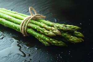 Fresh green asparagus bundle on wet surface photo