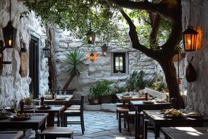 Charming restaurant tables set outdoors under a tree in a stone courtyard photo