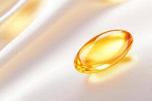 Macro shot captures a single golden gel capsule reflecting soft light on a smooth white surface photo