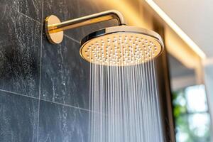 Luxurious rainfall showerhead delivering a refreshing cascade of water against a black marble wall in a serene spa-like bathroom setting photo