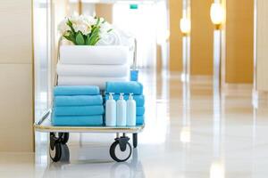 Fresh towels and toiletries arranged neatly on a service cart in a luxurious hotel hallway during daytime photo