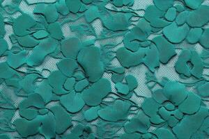 Detailed textile pattern featuring floral designs in a vibrant teal color on a delicate lace backdrop photo