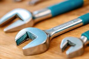 Collection of various metal wrenches displayed on a wooden surface in a workshop setting during daylight hours photo