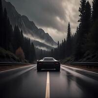A dark sports car drives on a wet mountain road through a forest of tall evergreen trees under a cloudy sky photo