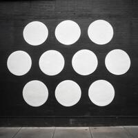 A striking black wall with nine large white circles painted in a grid pattern photo