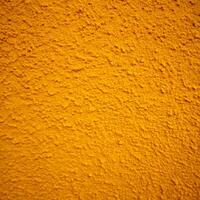 Closeup of a textured orange wall surface showing bumpy and grainy details photo