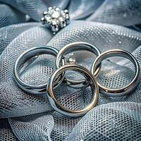 Three elegant silver wedding rings rest on a delicate silver mesh fabric background, creating a luxurious and romantic photo