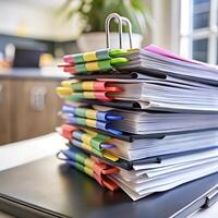A Large Stack of Documents Secured with Colorful Binder Clips on a Laptop photo