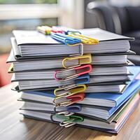 A Stack of Documents Secured with Colorful Binder Clips on a Wooden Table photo