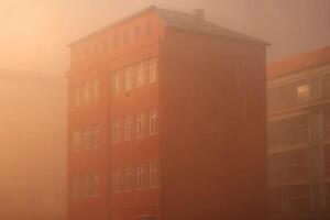 A building is seen in the fog in front of a building photo