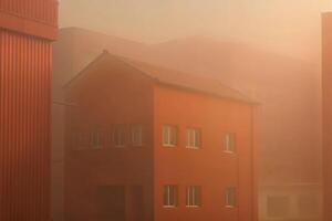 A building is shown in the fog with a red roof photo
