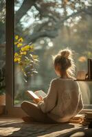 A woman sitting on the floor reading a book photo