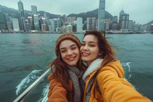 Two young women taking a selfie on a boat in hong kong photo