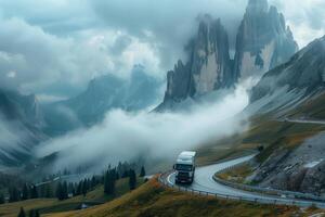 A truck driving down a mountain road with clouds in the background photo