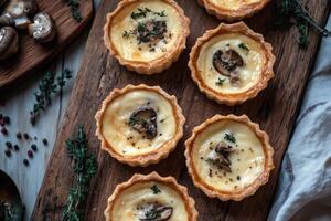 Mini chicken and mushroom quiches arranged on a rustic wooden board enhancing their golden crust and creamy filling photo