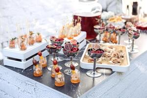 Elegant catering setup with glasses of figs and berries on display. Small jars of shrimp and tomatoes are arranged on a stylish table. photo