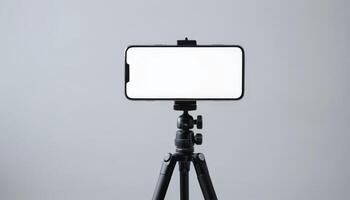 A smartphone mounted on a tripod with a blank white screen, suitable for recording videos, taking pictures, or content creation in various environments. photo