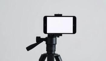 A smartphone mounted on a tripod with a blank screen, ideal for recording, streaming, or creating content in various settings. photo