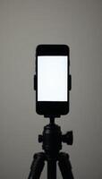 A smartphone secured on a tripod with a white screen, designed for content creation and streaming, ideal for mobile photography or vlogging setups. photo
