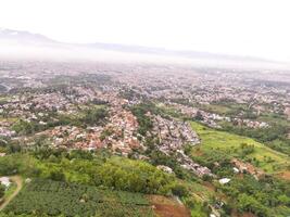Aerial Landscape view of foggy sky above mountains at dawn. High angle view of Mountain and cityscape in valley. Panorama of Highland in Bandung. photo