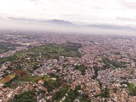 Aerial view of Residential District and Neighborhood in foggy morning. Suburbs of Bandung in West Java, Indonesia, photographed from above. Wide angle panoramic photo suitable for web banners