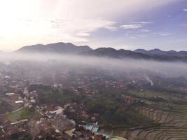 Bandung, Indonesia. Aerial Landscape view of foggy sky above mountains at dawn. High angle view of Mountain and cityscape in valley. Panorama of Highland in Bandung. Asia photo
