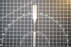 Cutter pen with cap on black striped rubber mat. Sharp cutting blade used to cut plastic parts. Metal tools and equipment. Tools for hobbyist robot model kit assembly. Negative Space photo