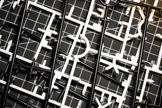 Runner frames in black and white stacked on a cutting mat. Plastic model kit frames left over from cutting parts. Abstract Backgrounds. Texture and Details. photo