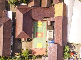 A soccer field in the middle of a brown-roofed building. Drone Landscape of an elite school, photographed from above. Wide angle panoramic photo suitable for web banner