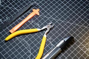 Tools set for building plastic model kits. Consisting of Nipper, Ink pen, cutting blade, plastic separator, and metal tweezer. Tools and equipment on black cutting mat. Toys and Model kits hobbies. photo