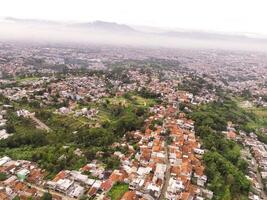 Aerial view of Residential District and Neighborhood in foggy morning. Suburbs of Bandung in West Java, Indonesia, photographed from above. Wide angle panoramic photo
