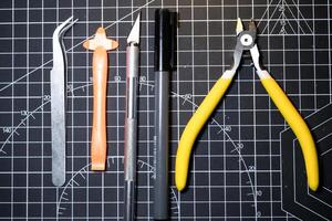 Tools set for building plastic model kits. Consisting of Nipper, Ink pen, cutting blade, plastic separator, and metal tweezer. Tools and equipment on black cutting mat. Toys and Model kits photo