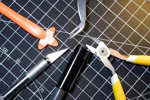 Tools for building plastic model kits. Consisting of Nipper, Ink pen, cutting blade, plastic separator, and metal tweezer. Tools and equipment on black cutting mat. Toys and Model kits hobbies. photo