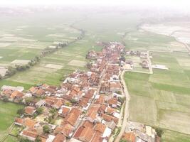 Cikancung, Indonesia. Aerial Landscape view of a remote village surrounded by rice field patches. High angle view of Residential District and agricultural fields. Panorama rural and suburban. Asia photo