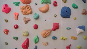 Climbing artificial rock climbing wall to practice mountain bouldering and climbing skills with colored grips and route markers for beginners. Bouldering track on simulated rock boulder walls. video